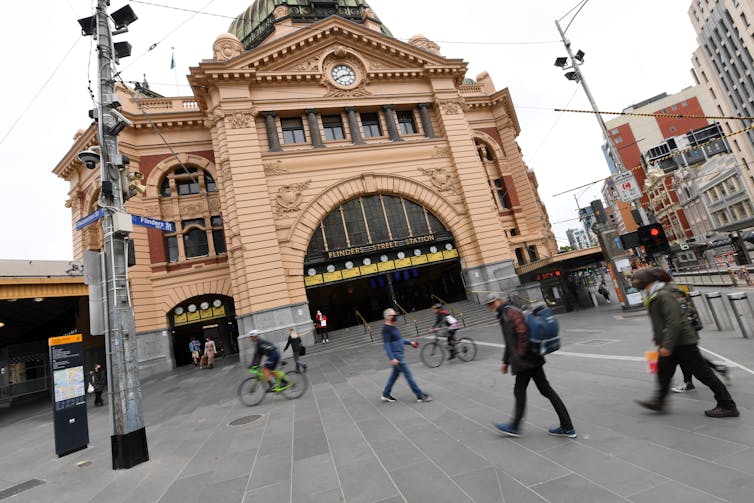 A handful of pedestrians walk on Melbourne streets.