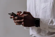 A man's hands are seen using a smartphone.