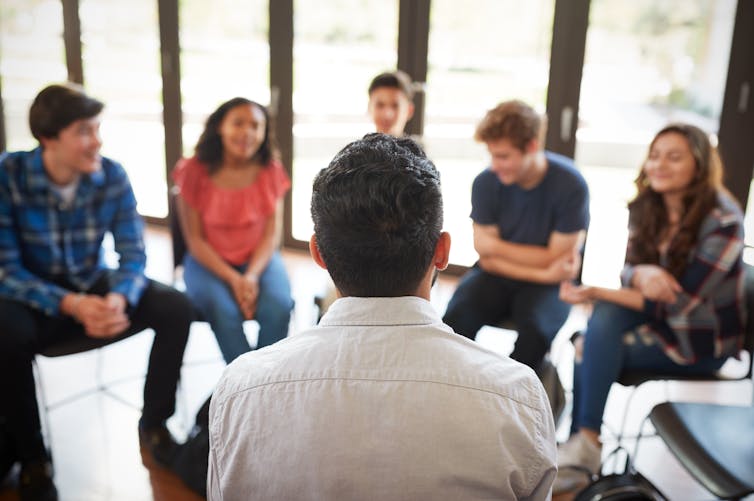 Young male tutor talks with class