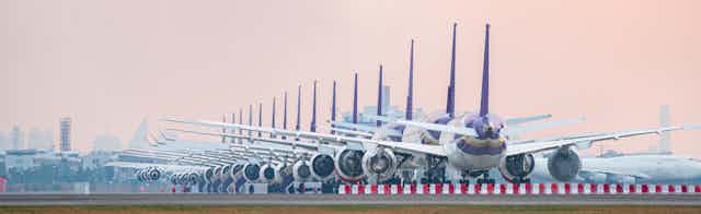 A row of grounded aeroplanes on an airport runway.