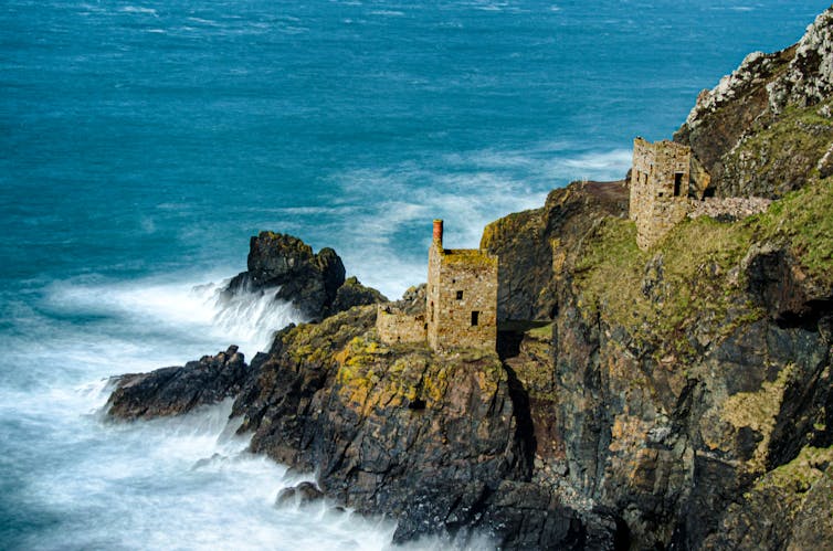 Crumbling mine on the coast with waves crashing below.