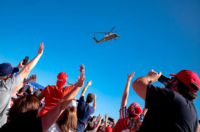 Trump rally attendees wave to his helicopter as he leaves.