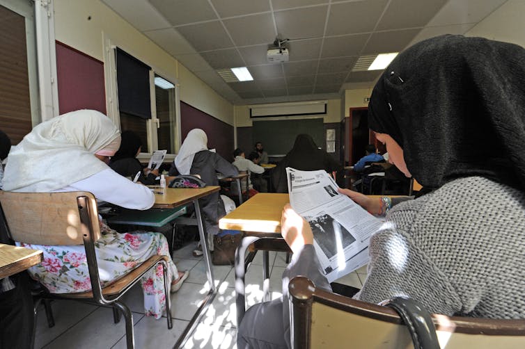 Pupils in headscarves sit at desks