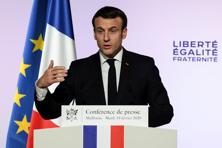 Macron speaks at a lectern with the French and EU flags behind him