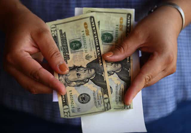 A woman counts money outside a U.S. remittance collection agency in San Isidro, El Salvador.