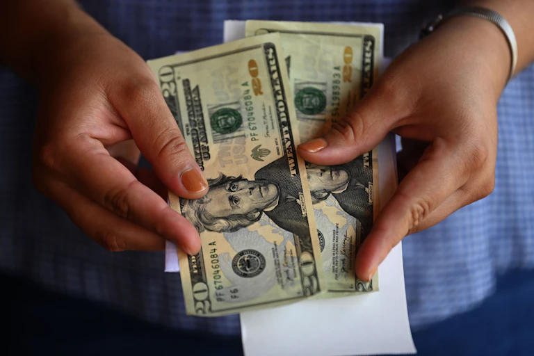 A woman counts money outside a U.S. remittance collection agency in San Isidro, El Salvador.