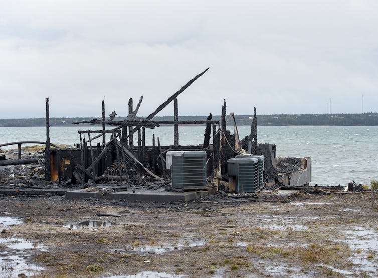 Debris from a burnt building next to the ocean.