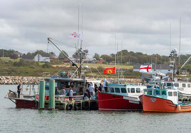 Fishing boats flying flags at dock and preparing to launch.