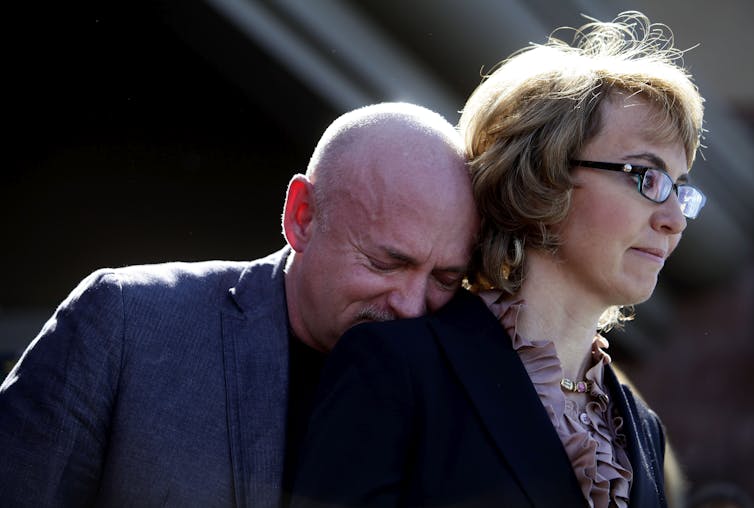 Kelly, crying, rests his head on Gabby Giffords' shoulder.