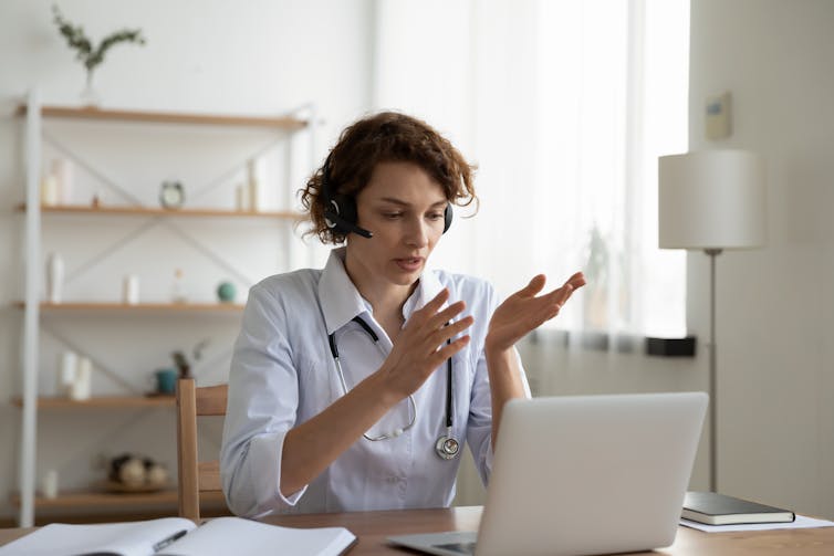 A female doctor speaks to someone on her laptop computer.