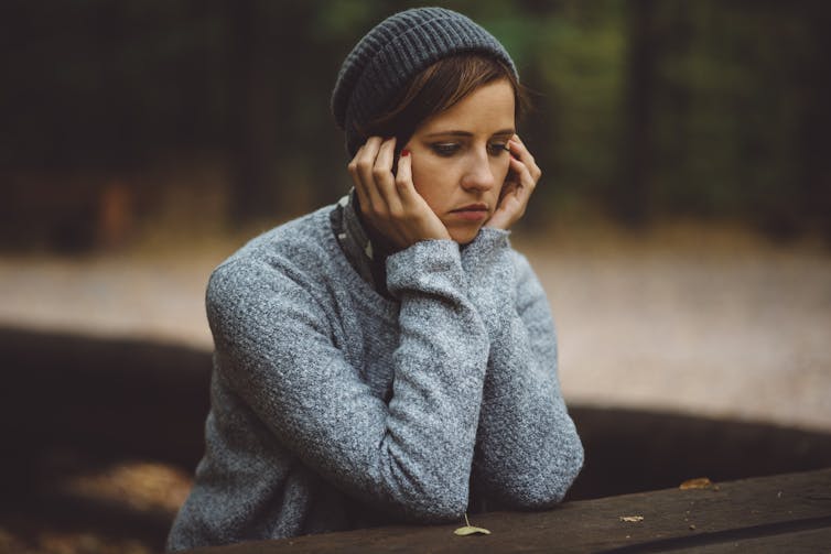 A young woman has her head in her hands.