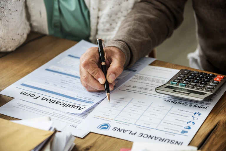 A person filling out forms with a calculator nearby