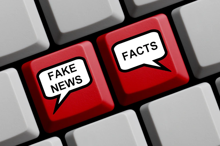 A computer keyboard with speech bubbles on two keys saying FAKE NEWS and FACTS