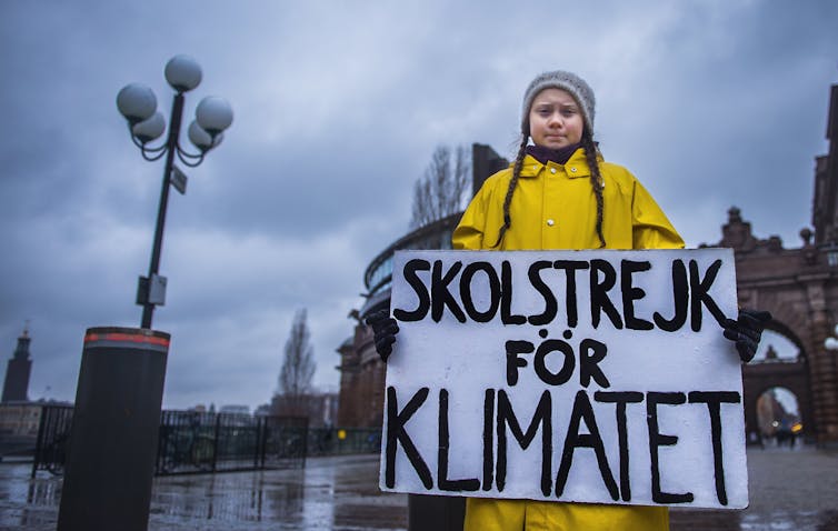 Thunberg holding a sign: Skolstrejk för klimatet