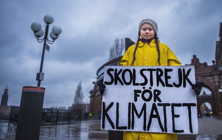 Thunberg holding a sign: Skolstrejk fÃ¶r klimatet