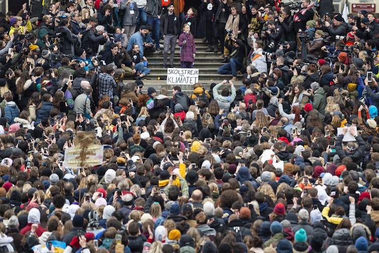 Thunberg speaks surrounded by a large crowd.