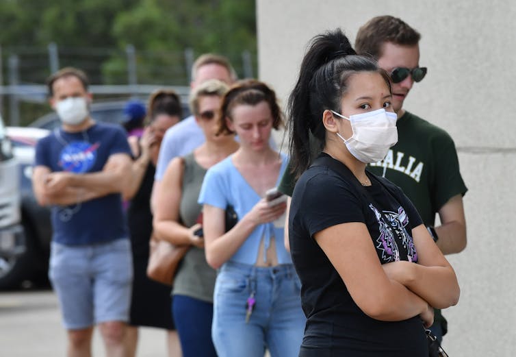 Woman wearing a mask, lining up to vote.