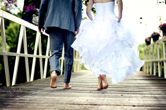 Bride and groom barefoot on a wooden deck or jetty