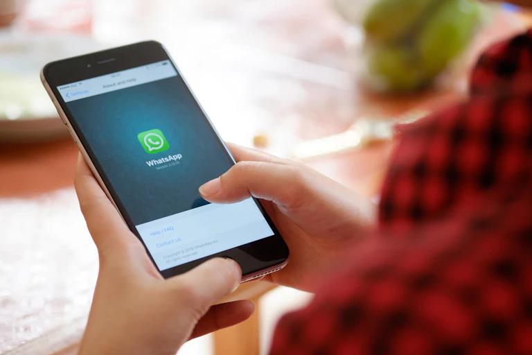 Persona manipulando con los pulgares un teléfono móvil con la aplicación WhatsApp abierta.
