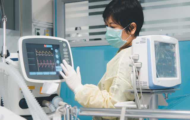 A nurse adjusting a ventilator in an ICU