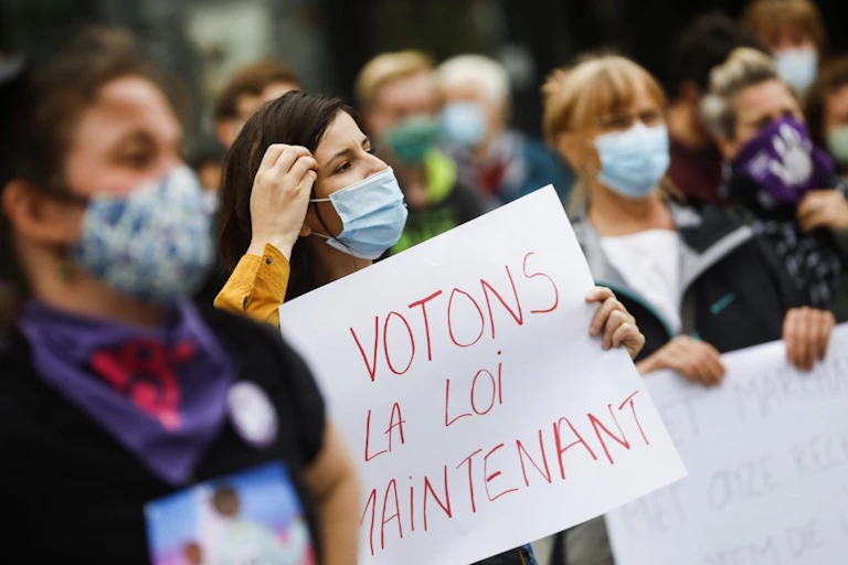Une militante, tenant une pancarte "votons la loi maintenant"
