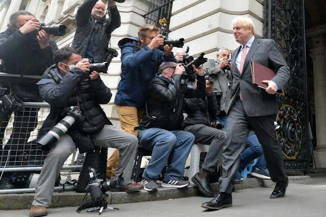Boris Johnson cheerfully greets the press.