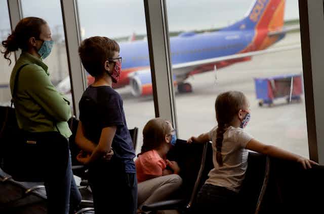 A family waits in an airport with masks on.