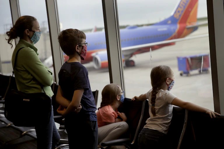 A family waits in an airport with masks on.