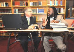 Two founders of the Pathways in Technology Early College High School sit at a table and talk.