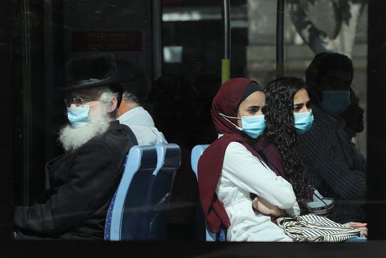 People sitting on a bus with masks in Israel