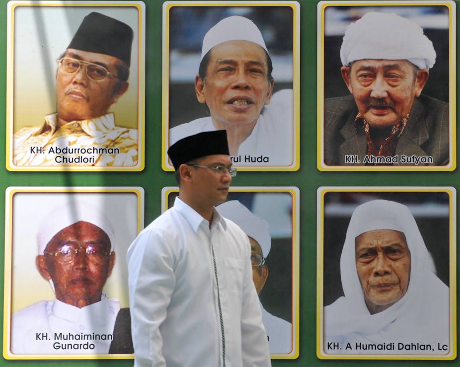 Seorang pria berjalan di depan gambar para pemimpin Muslim di Jawa Timur, Indonesia.