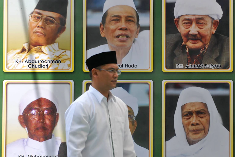 Seorang pria berjalan di depan gambar para pemimpin Muslim di Jawa Timur, Indonesia.