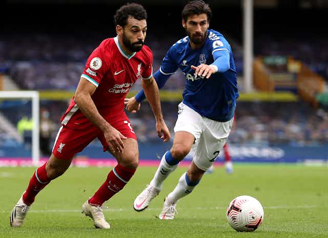 Two footballers competing in a Premier League match between Liverpool and Everton.