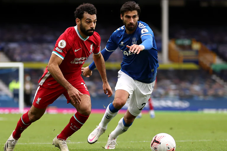Two footballers competing in a Premier League match between Liverpool and Everton.