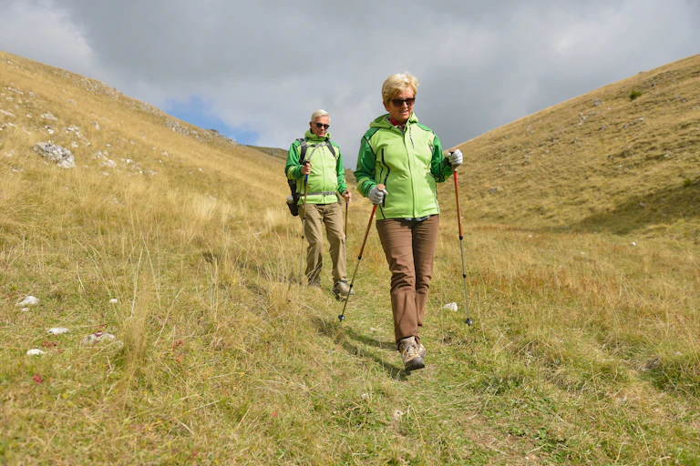 Older couple hike downhill.