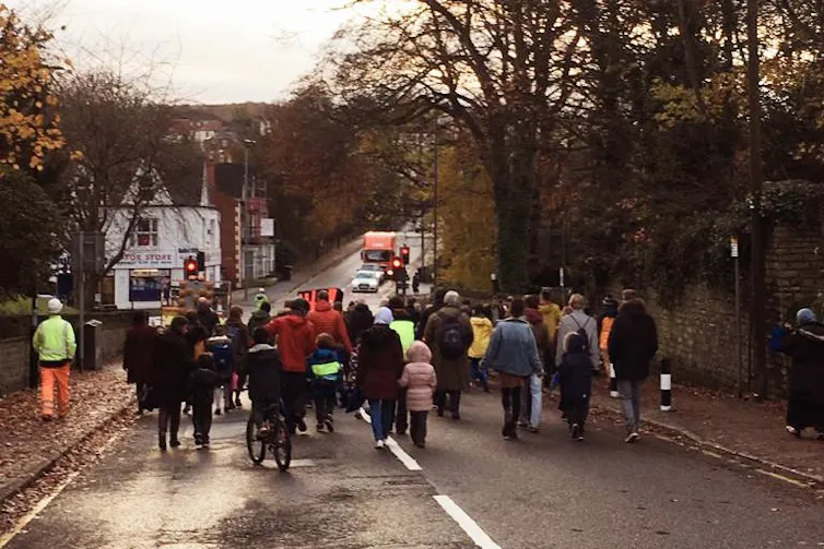 Adults and children walking and cycling in the road.