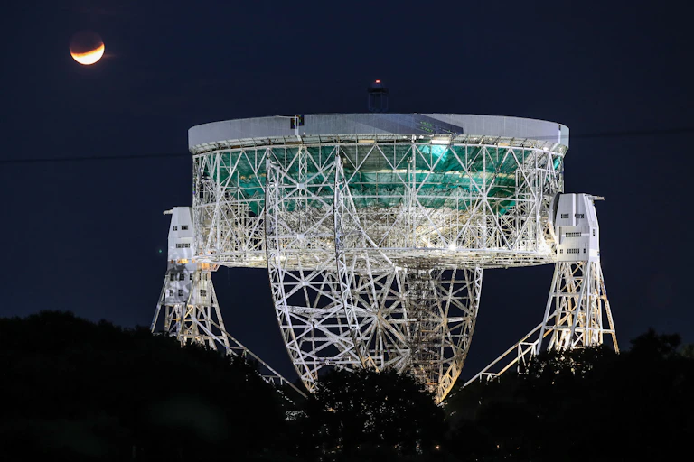 Partial lunar eclipse seen above a huge radio telescope.