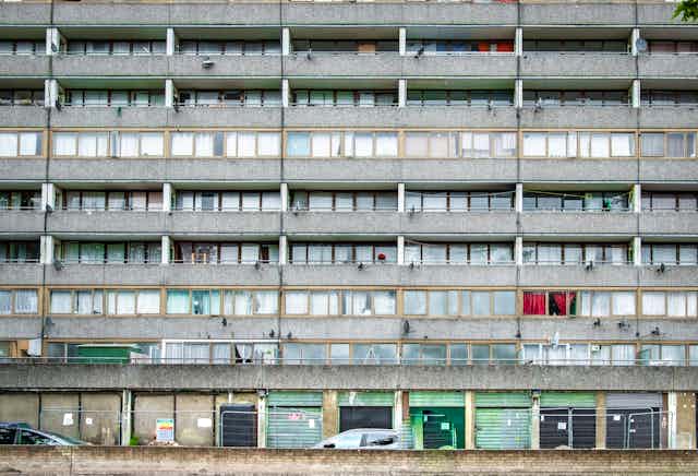 Shabby down at heel London council estate with boarded up and shuttered shops.