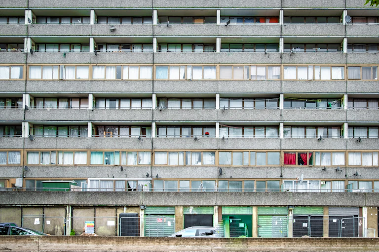 Shabby down at heel London council estate with boarded up and shuttered shops.