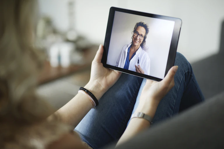 Young woman having online meeting with female healthcare person in white coat.