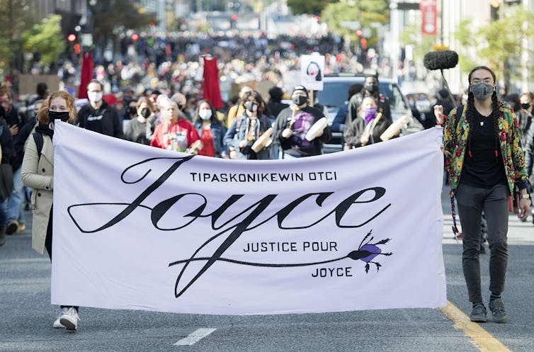 People marching and holding a banner that says Justice for Joyce
