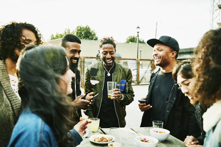 friends drinking and laughing at an outdoor bar