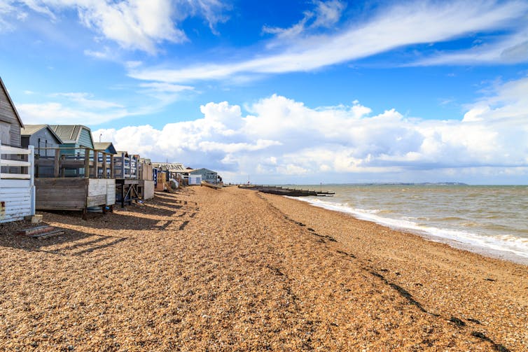 A large beach with wooden beach huts.