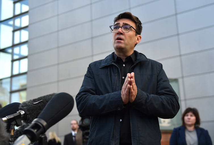 Andy Burnham addressing a public audience outside.