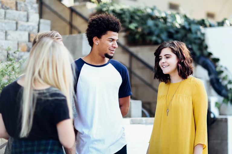 Three young people chat outdoors.