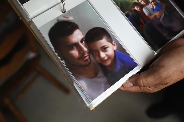 Photo album held open showing a picture of a young man and little boy