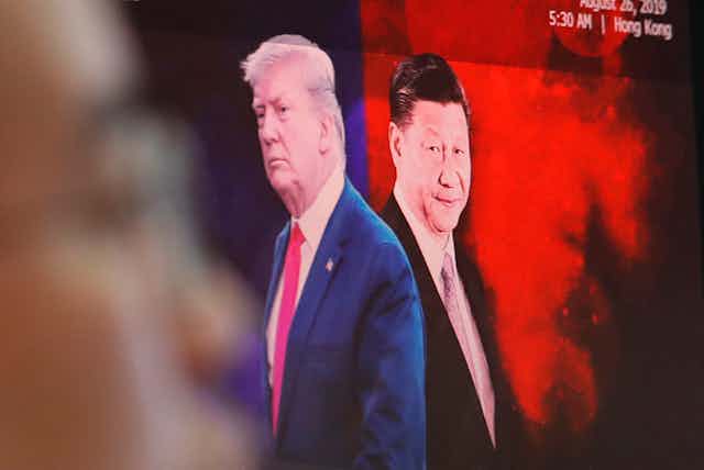 A computer screen shows images of Chinese President Xi Jinping and U.S. President Donald Trump as a currency trader works at the foreign exchange dealing room of the KEB Hana Bank headquarters in Seoul.