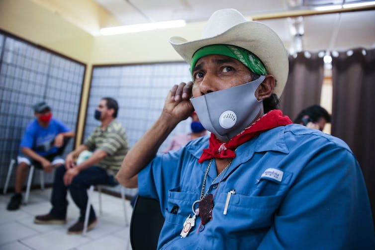A man partially wearing a mask waits for an employment interview in Imperial County, California.