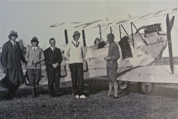 Millicent Bryant with a plane and other aviators.