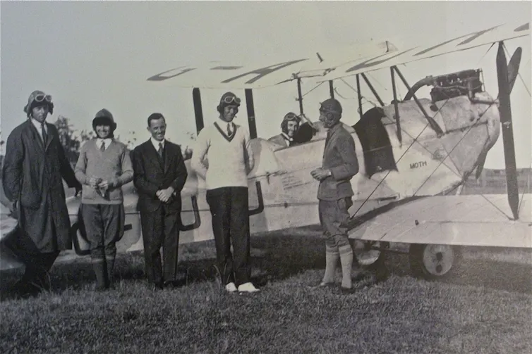 Millicent Bryant with a plane and other aviators.